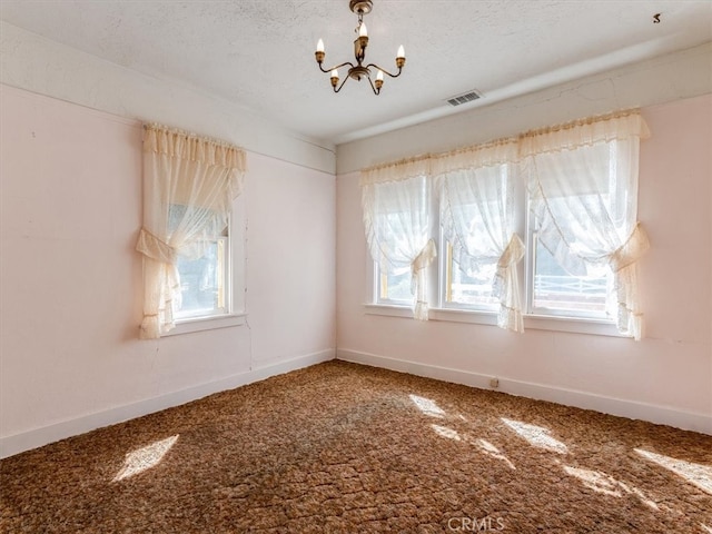 spare room featuring a notable chandelier, plenty of natural light, and carpet