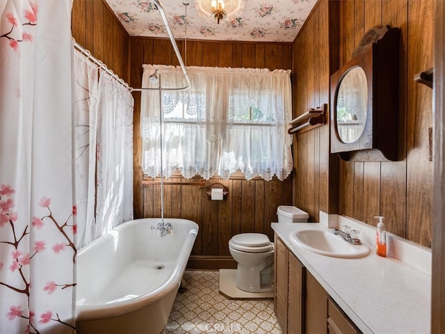 full bathroom featuring wooden walls, vanity, and toilet