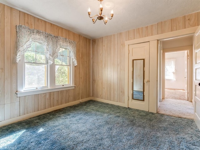 unfurnished bedroom with an inviting chandelier, wooden walls, carpet flooring, and multiple windows