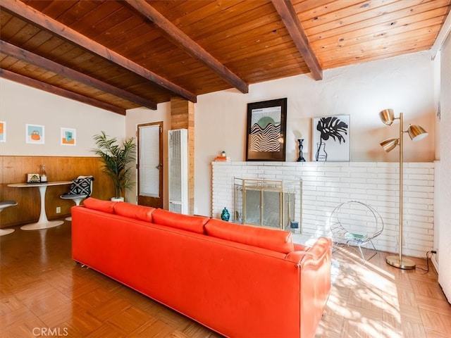 living room with wood walls, parquet floors, a fireplace, vaulted ceiling with beams, and wooden ceiling