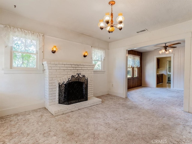 unfurnished living room featuring ceiling fan with notable chandelier, carpet, and a fireplace