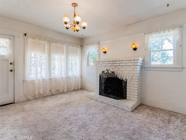 unfurnished living room with carpet floors, a textured ceiling, a chandelier, and a brick fireplace