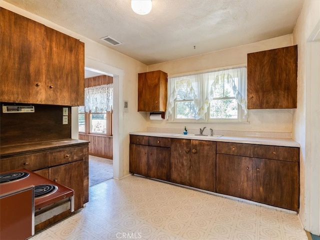 kitchen featuring a textured ceiling, range with electric stovetop, and sink