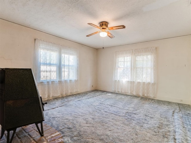 unfurnished room with a textured ceiling, carpet flooring, and ceiling fan