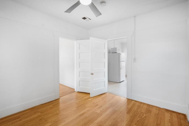 unfurnished bedroom with ceiling fan, white refrigerator, a closet, and light wood-type flooring