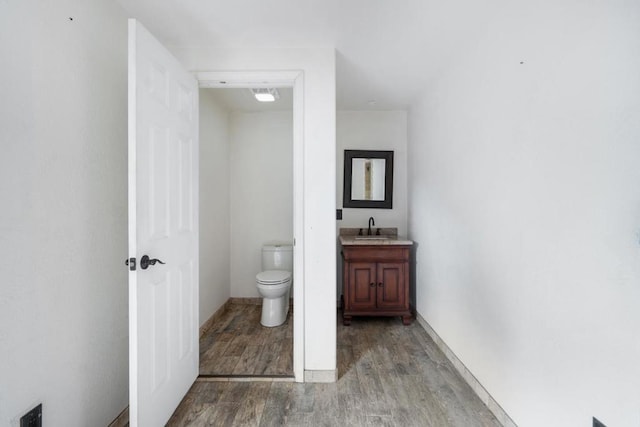 bathroom with toilet, hardwood / wood-style flooring, and vanity