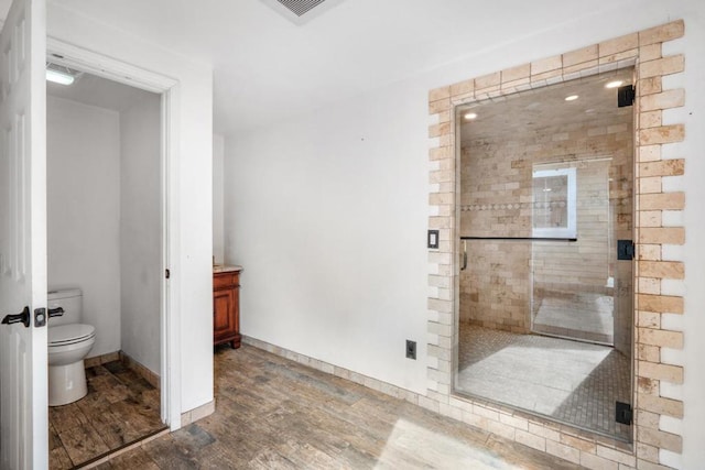 bathroom with hardwood / wood-style flooring, toilet, and an enclosed shower