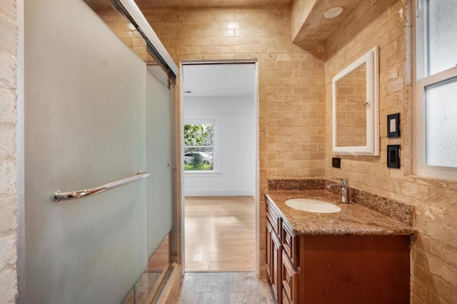 bathroom with vanity, wood-type flooring, and brick wall