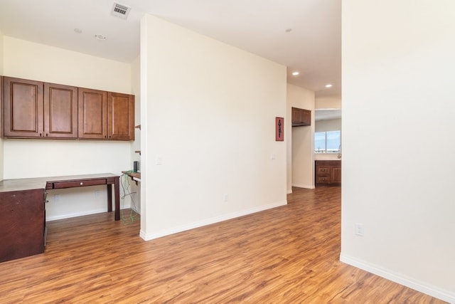 spare room with light wood-type flooring and built in desk