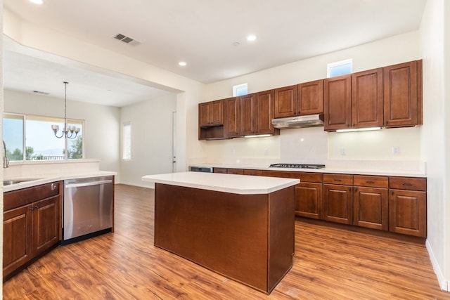 kitchen featuring hardwood / wood-style flooring, a notable chandelier, a kitchen island, appliances with stainless steel finishes, and decorative light fixtures