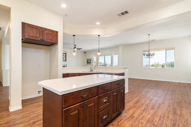 kitchen with light hardwood / wood-style floors, a center island, and decorative light fixtures