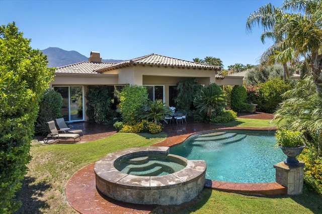 back of house with a pool with hot tub, a patio area, a mountain view, and a yard