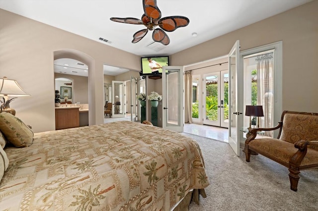 carpeted bedroom featuring access to outside, ensuite bath, ceiling fan, and french doors