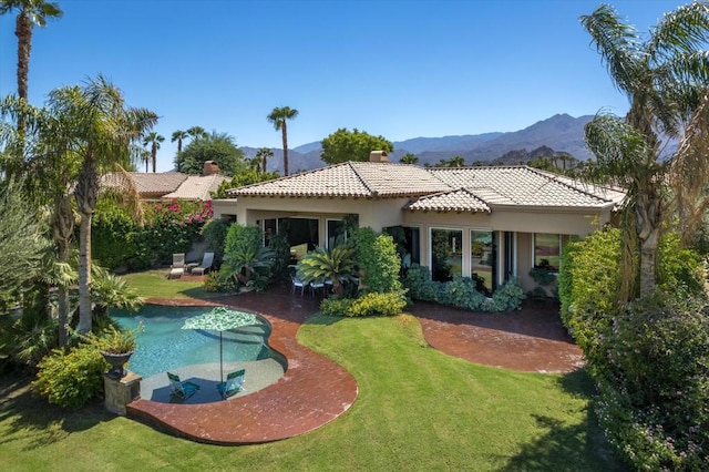 back of property with a lawn, a mountain view, and a patio