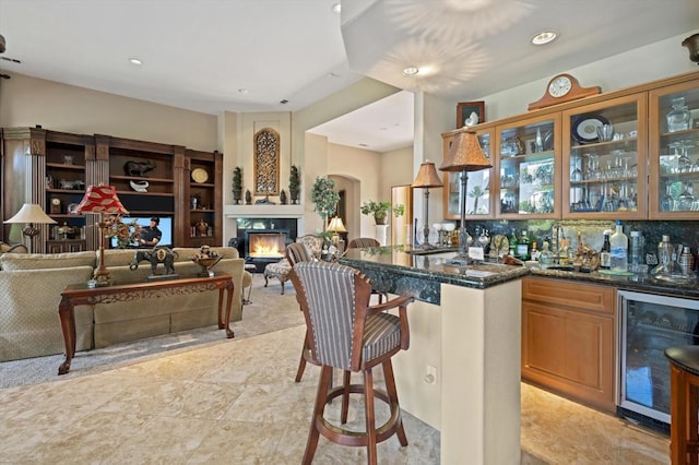 kitchen featuring a kitchen breakfast bar, wine cooler, decorative backsplash, and dark stone counters