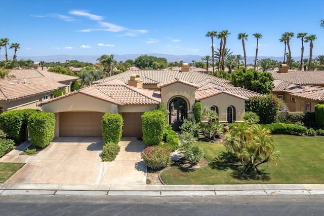 mediterranean / spanish home featuring a front yard and a garage