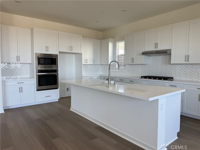15949 Conservatory Dr, Fontana, CA 92336 - kitchen featuring appliances with stainless steel finishes, decorative backsplash, dark wood-style flooring, under cabinet range hood, and white cabinets