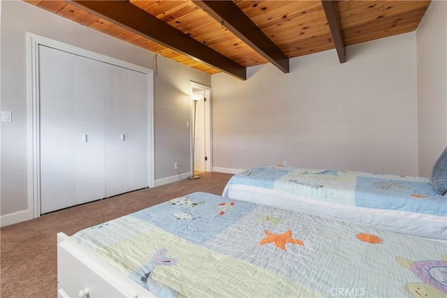 carpeted bedroom with a closet, beamed ceiling, and wood ceiling