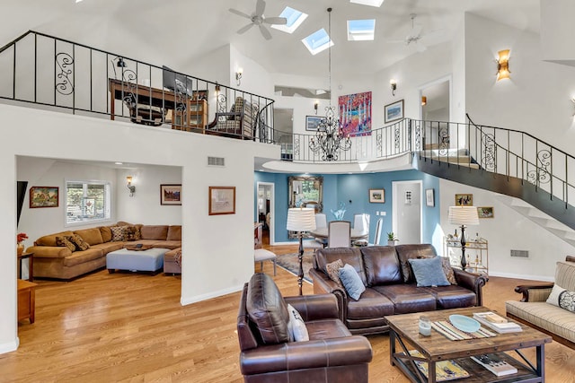 living room featuring wood-type flooring, a skylight, high vaulted ceiling, and ceiling fan