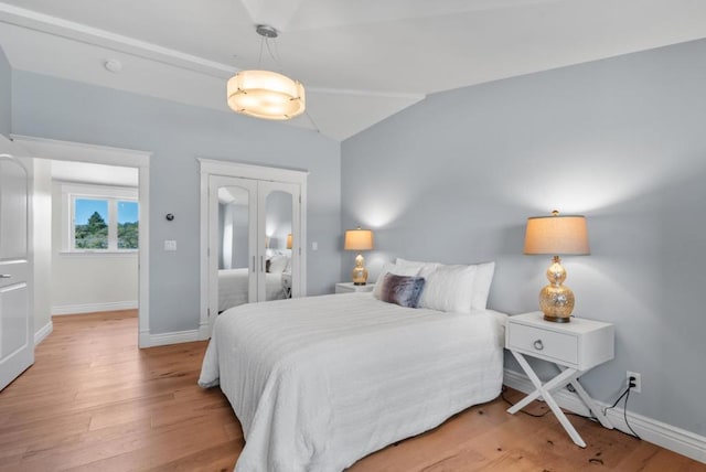 bedroom featuring light wood-type flooring and vaulted ceiling