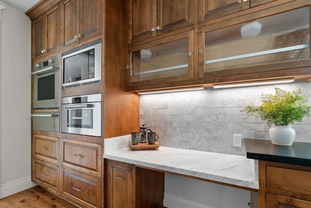 kitchen featuring hardwood / wood-style flooring, light stone counters, appliances with stainless steel finishes, and tasteful backsplash