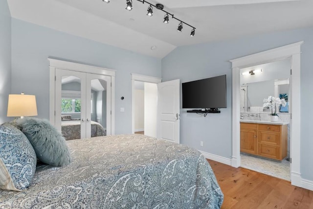 bedroom featuring french doors, sink, vaulted ceiling, hardwood / wood-style flooring, and connected bathroom