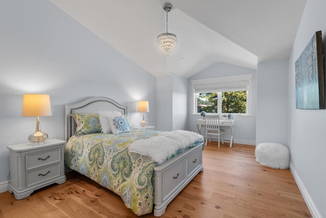 bedroom with an inviting chandelier, vaulted ceiling, and light wood-type flooring