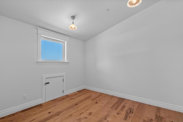 spare room featuring light hardwood / wood-style floors and lofted ceiling