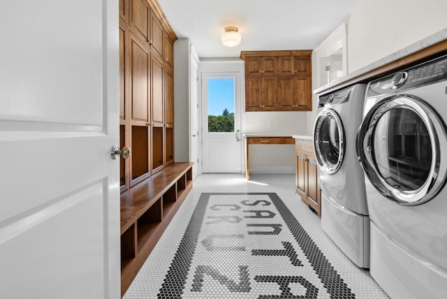 clothes washing area with cabinets and washer and clothes dryer