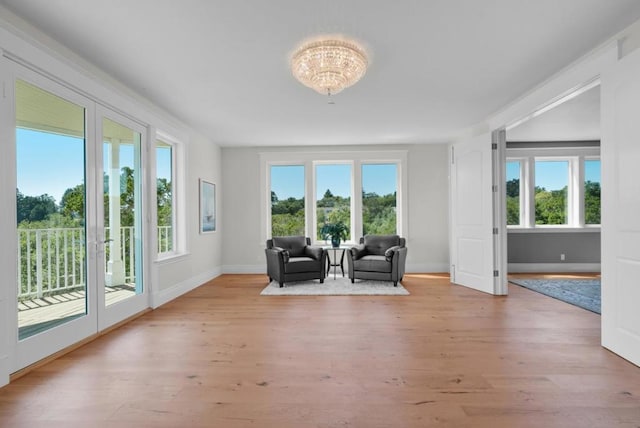 unfurnished room with a wealth of natural light, an inviting chandelier, and light wood-type flooring