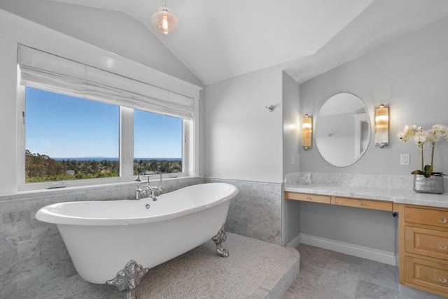 bathroom featuring vanity, vaulted ceiling, tile patterned flooring, tile walls, and a tub to relax in