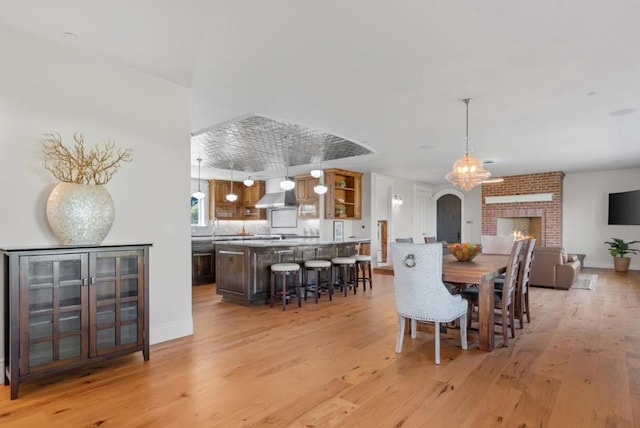 dining area with light wood-type flooring, a brick fireplace, and sink