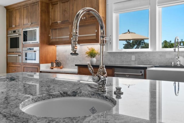 kitchen featuring tasteful backsplash, dark stone countertops, sink, and stainless steel appliances