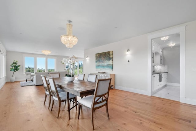 dining space with a notable chandelier, sink, and light hardwood / wood-style flooring