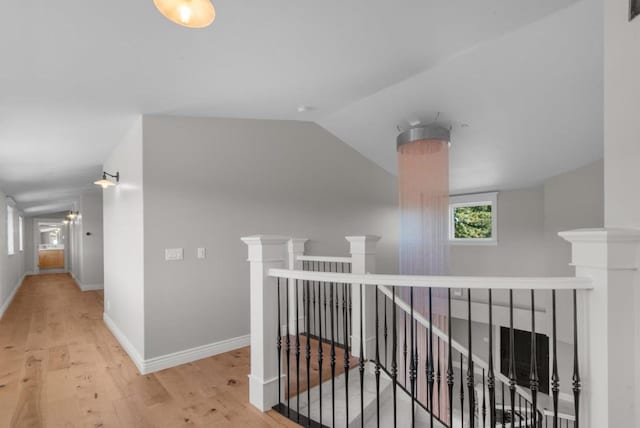 corridor with light hardwood / wood-style floors and lofted ceiling