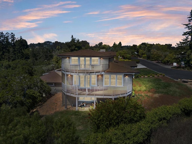 back house at dusk featuring a balcony