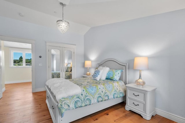 bedroom featuring light hardwood / wood-style floors, an inviting chandelier, and lofted ceiling