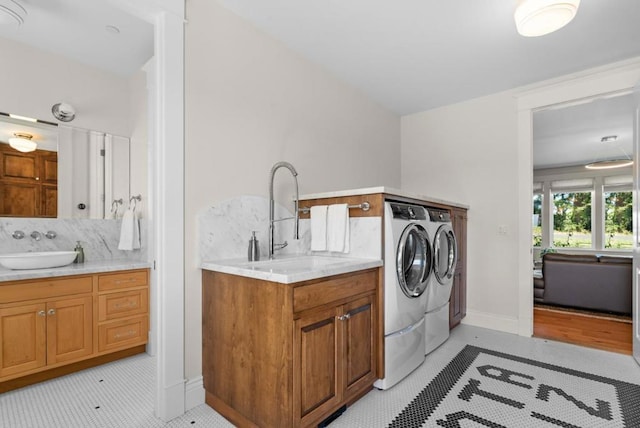 laundry area featuring washing machine and dryer, light tile patterned floors, and sink