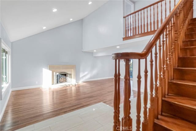 stairs with high vaulted ceiling and wood-type flooring