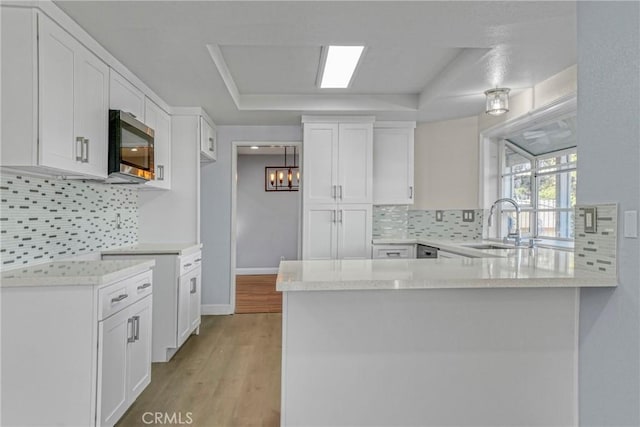 kitchen featuring light hardwood / wood-style flooring, kitchen peninsula, backsplash, and white cabinets