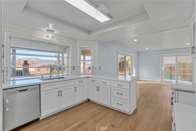 kitchen featuring white cabinetry, a raised ceiling, light wood-type flooring, dishwasher, and sink