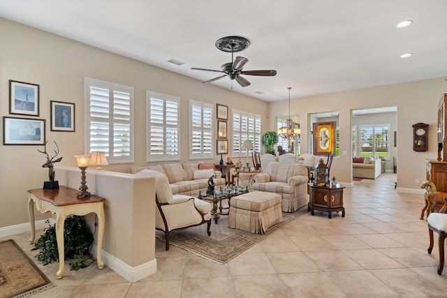 living room with ceiling fan with notable chandelier, plenty of natural light, and light tile patterned flooring