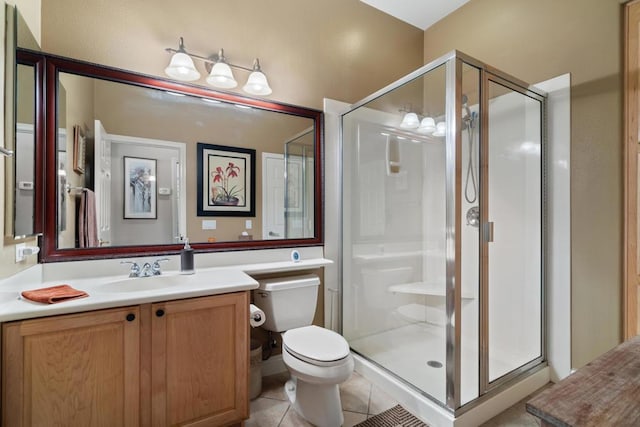 bathroom featuring tile patterned flooring, vanity, toilet, and a shower with shower door