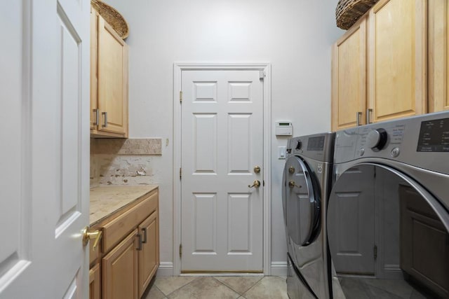 laundry room featuring cabinets, light tile patterned floors, and washer and dryer