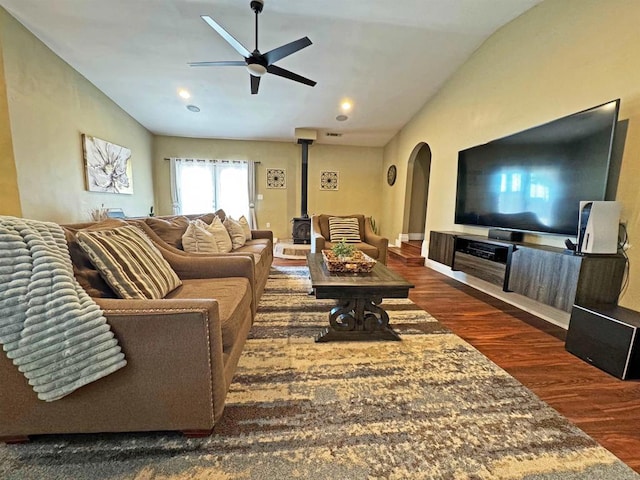 living room featuring vaulted ceiling, ceiling fan, a wood stove, and dark hardwood / wood-style flooring