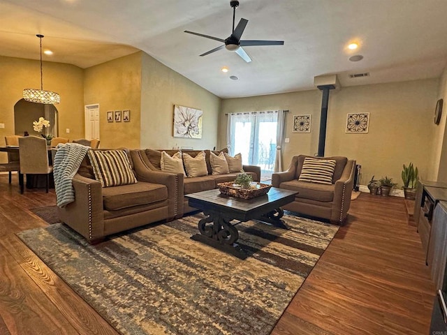 living room featuring lofted ceiling, ceiling fan, a wood stove, and dark hardwood / wood-style flooring