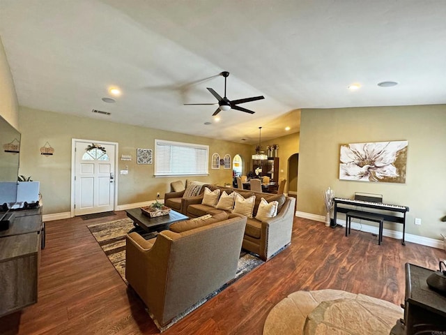 living room featuring ceiling fan with notable chandelier and dark hardwood / wood-style flooring