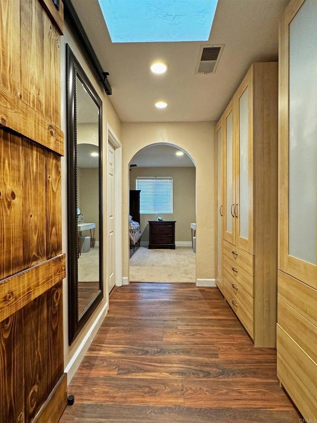 hall with a barn door and dark hardwood / wood-style flooring