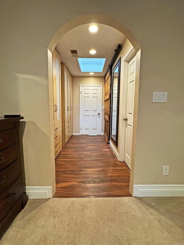 hallway with dark hardwood / wood-style floors and a skylight