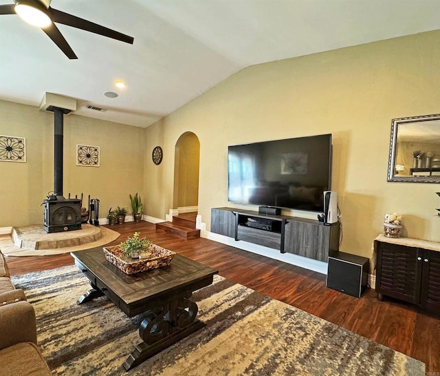 living room with lofted ceiling, dark wood-type flooring, a wood stove, and ceiling fan